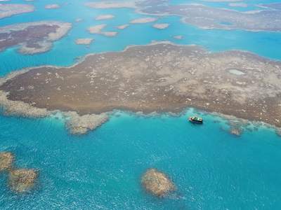 O recife raso e a água azul em volta do barco