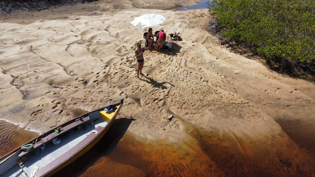 A parada no banco de areia, com o guarda-sol aberto e o barco encostado