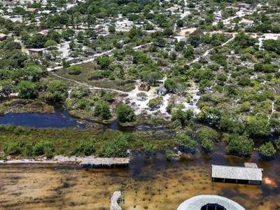 A aldeia à beira do rio, com a oca e o mar ao fundo