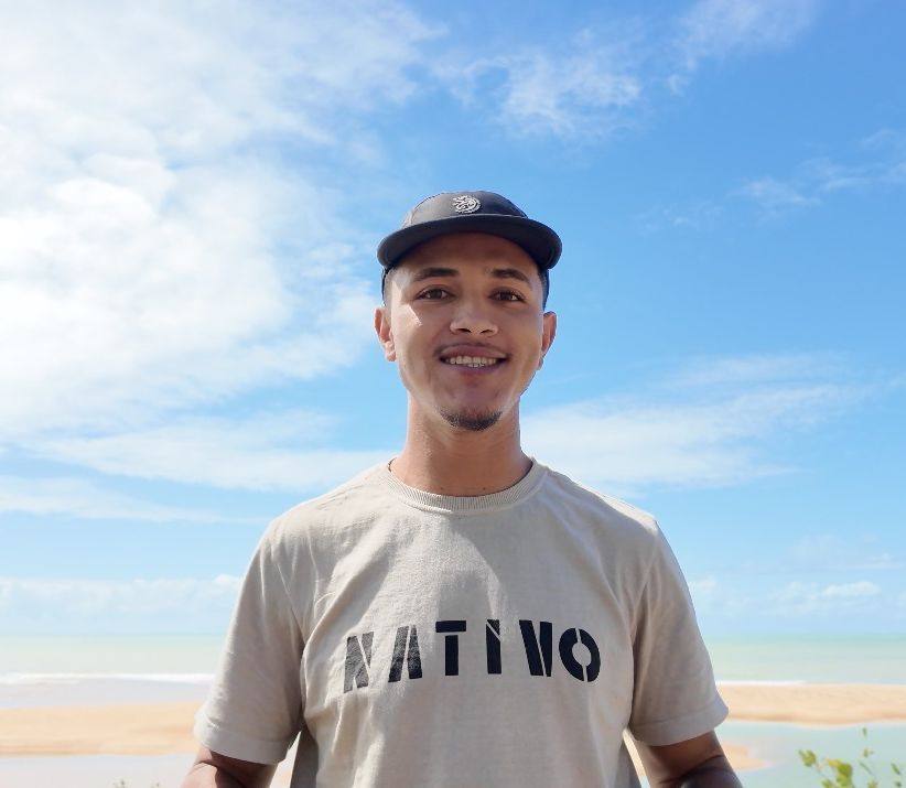 Fernando de camiseta Nativo, com a praia de Corumbau ao fundo