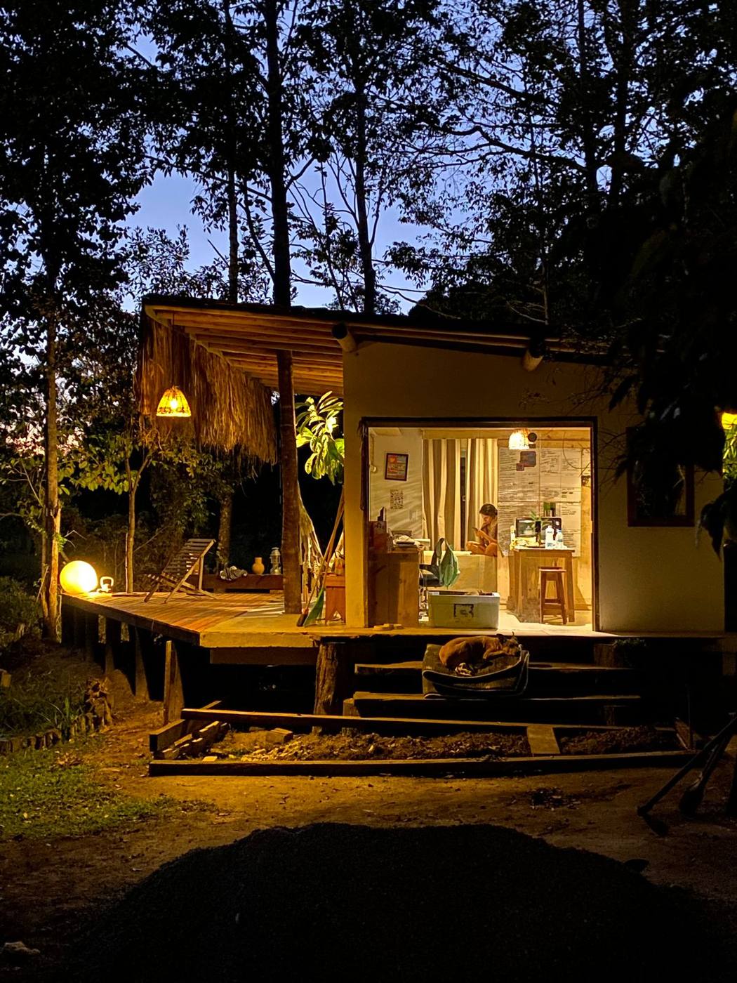 Cabana de madeira acesa ao anoitecer, no meio da mata