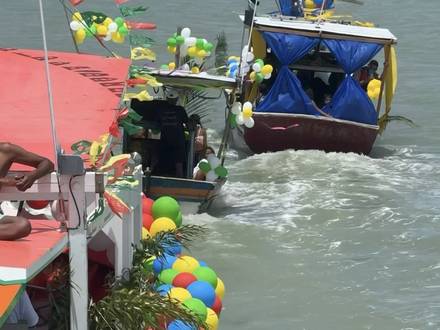 Os barcos enfeitados em movimento, com a praia ao fundo