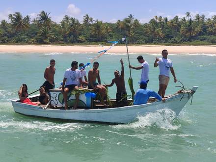 Um barco da procissão passando em frente aos coqueiros